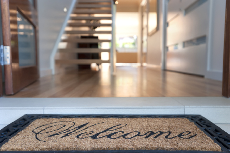 Welcome mat in front of open door of house for sale