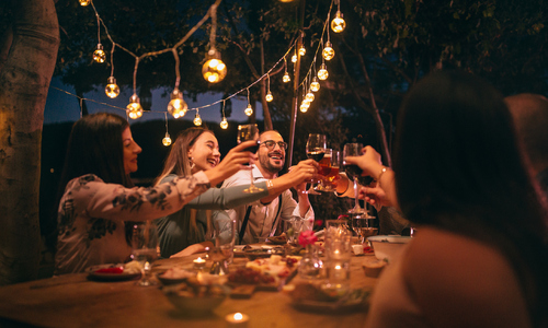 Friends toasting with wine and beer at rustic dinner party